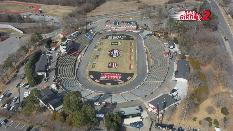 Aerial view of a NASCAR race with packed grandstands and cars racing on the track