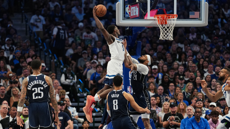 Professional basketball player performing a spectacular slam dunk in an NBA arena