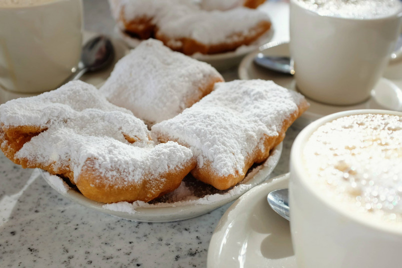 Traditional New Orleans coffee with chicory being served alongside powdered sugar beignets