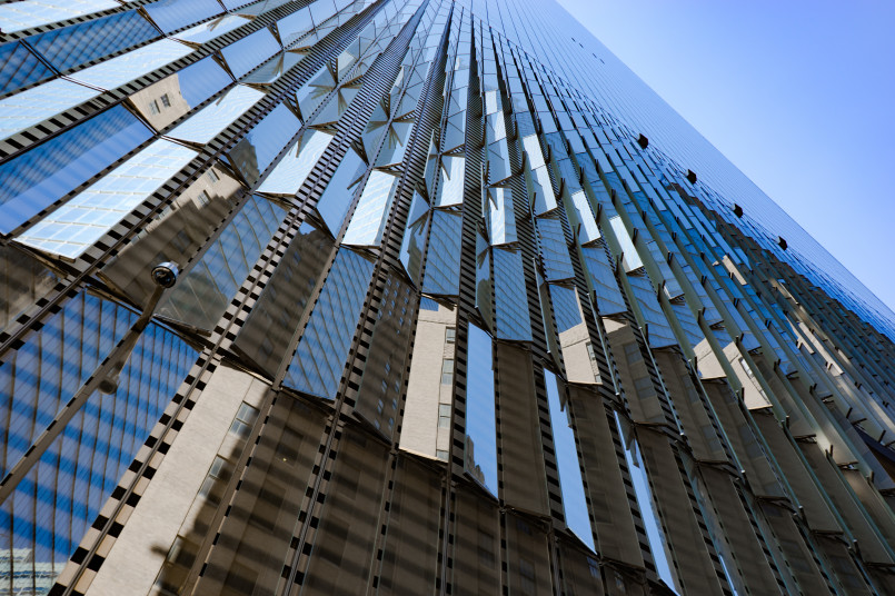 Close-up of One World Trade Center's reflective glass facade against blue sky