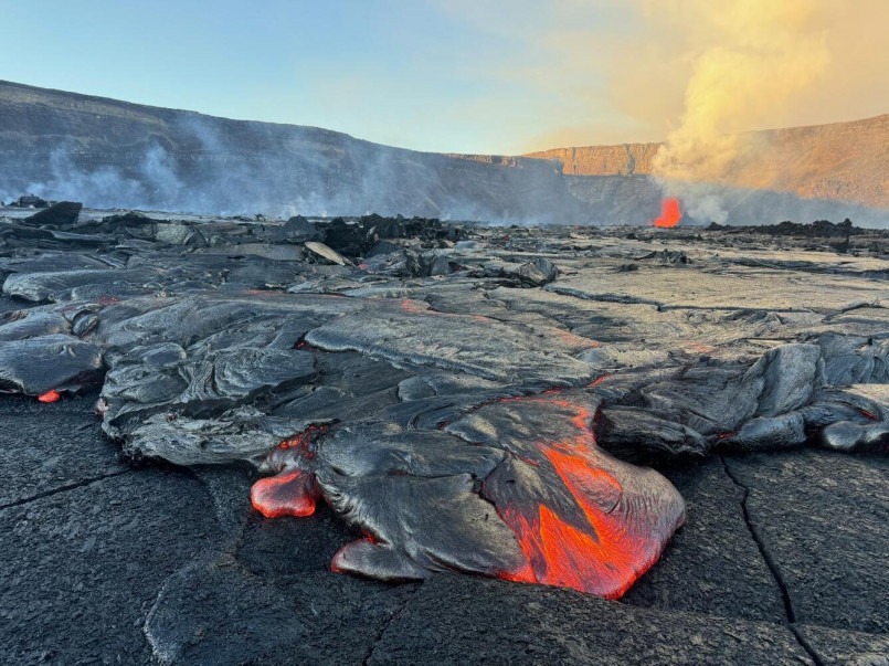 Red-hot lava flow from Kilauea volcano entering the ocean with steam clouds rising