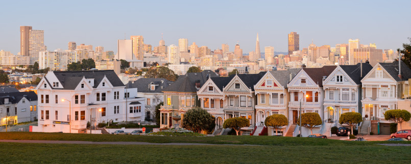 Row of colorful Victorian 'Painted Ladies' houses with San Francisco skyline in background