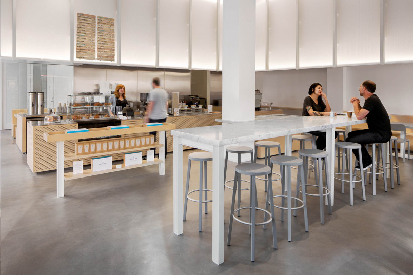 Customers waiting in line at a sleek, minimalist Blue Bottle Coffee location in San Francisco