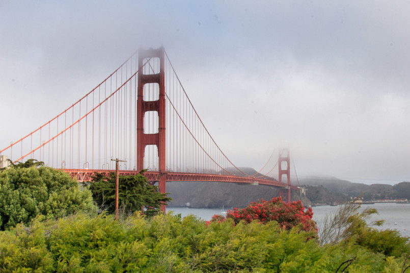 San Francisco's Golden Gate Bridge partially covered in fog with city skyline in background