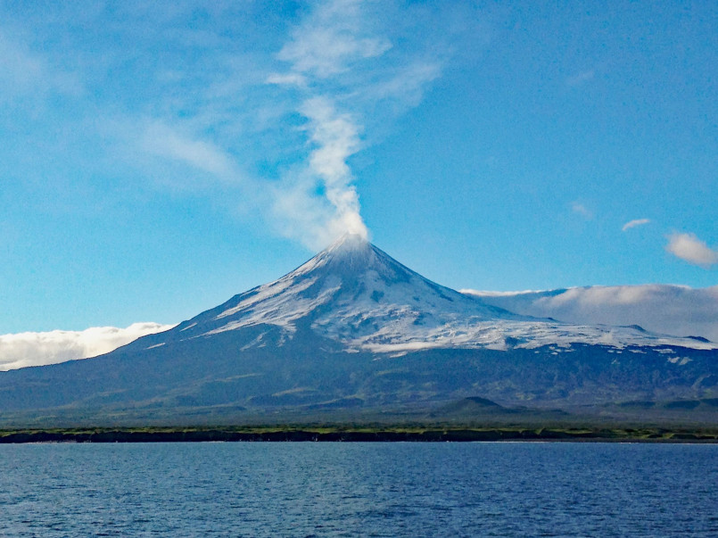 Snow-capped Mount Shishaldin volcano on Unimak Island with steam rising from its peak