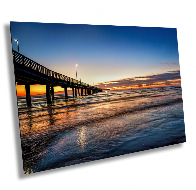 Sunrise over calm Gulf of Mexico waters with golden light illuminating white sand beach
