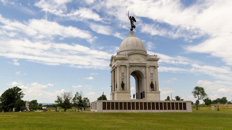Stone monuments at Gettysburg National Military Park with rolling hills and battlefield landscapes in the background