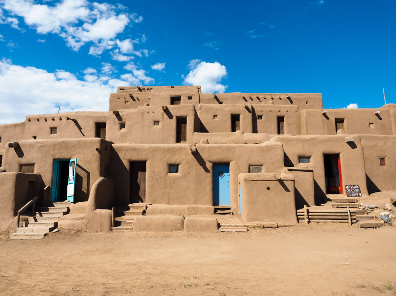 Taos Pueblo adobe buildings New Mexico Ancient multi-story adobe buildings at Taos Pueblo with traditional ladders and blue doorways