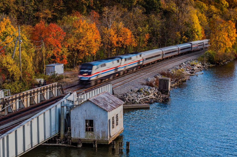 The Adirondack train traveling alongside the Hudson River surrounded by brilliant fall foliage in red and gold