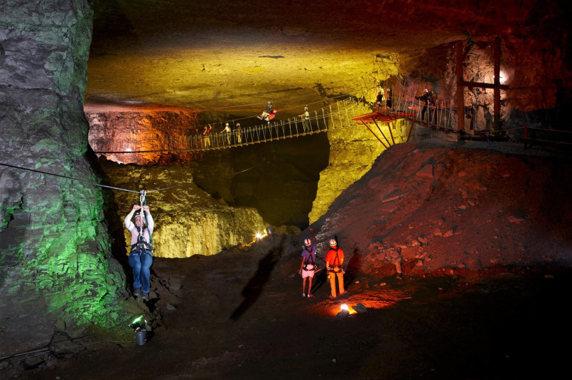 Zip line course through illuminated underground limestone cavern