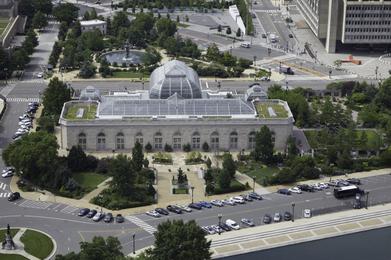 Glass conservatory building with white dome against blue sky