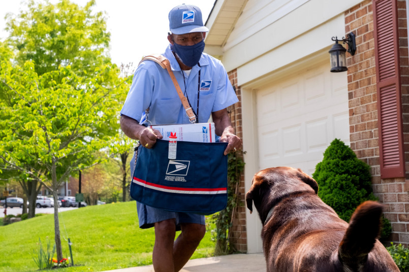 Usps mail carrier delivering packages neighborhood Postal worker in uniform delivering mail to residential mailbox