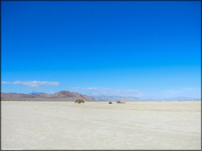 Vast, cracked white playa of Black Rock Desert stretching to distant mountains under blue sky