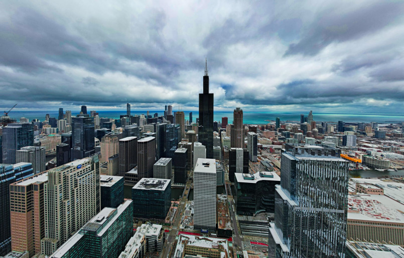 Tourists standing on the glass Skydeck ledge of Willis Tower with Chicago skyline below