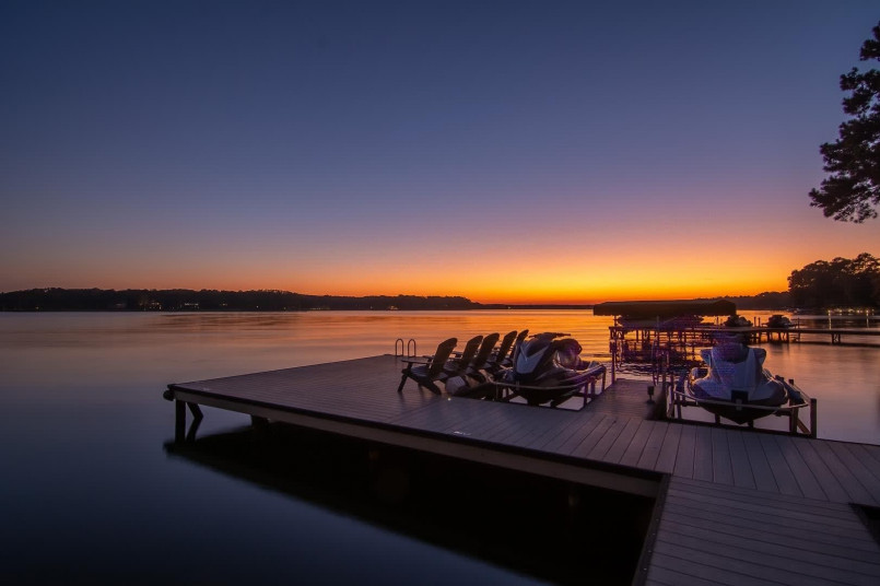 Lake Oconee Georgia sunset dock Wooden dock extending into Lake Oconee at sunset with trees silhouetted against orange sky