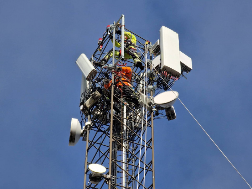 Workers installing 5G network equipment on a communications tower
