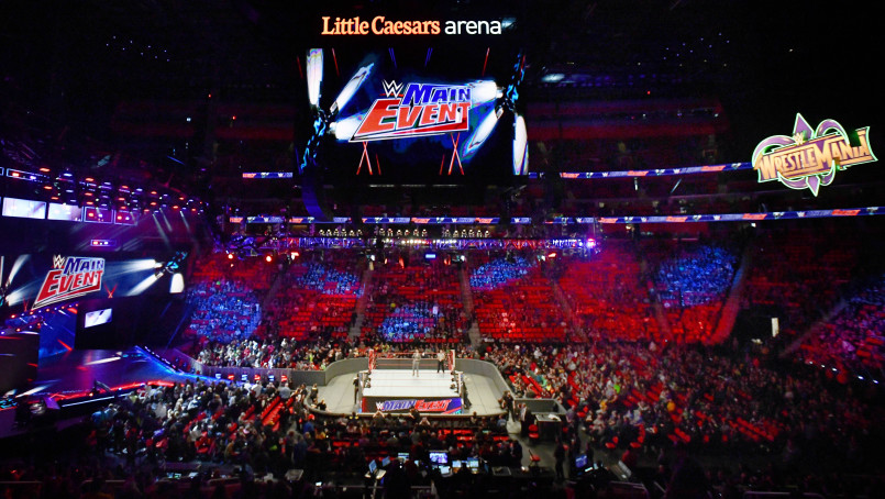 Packed arena during a WWE wrestling event with dramatic lighting and staging